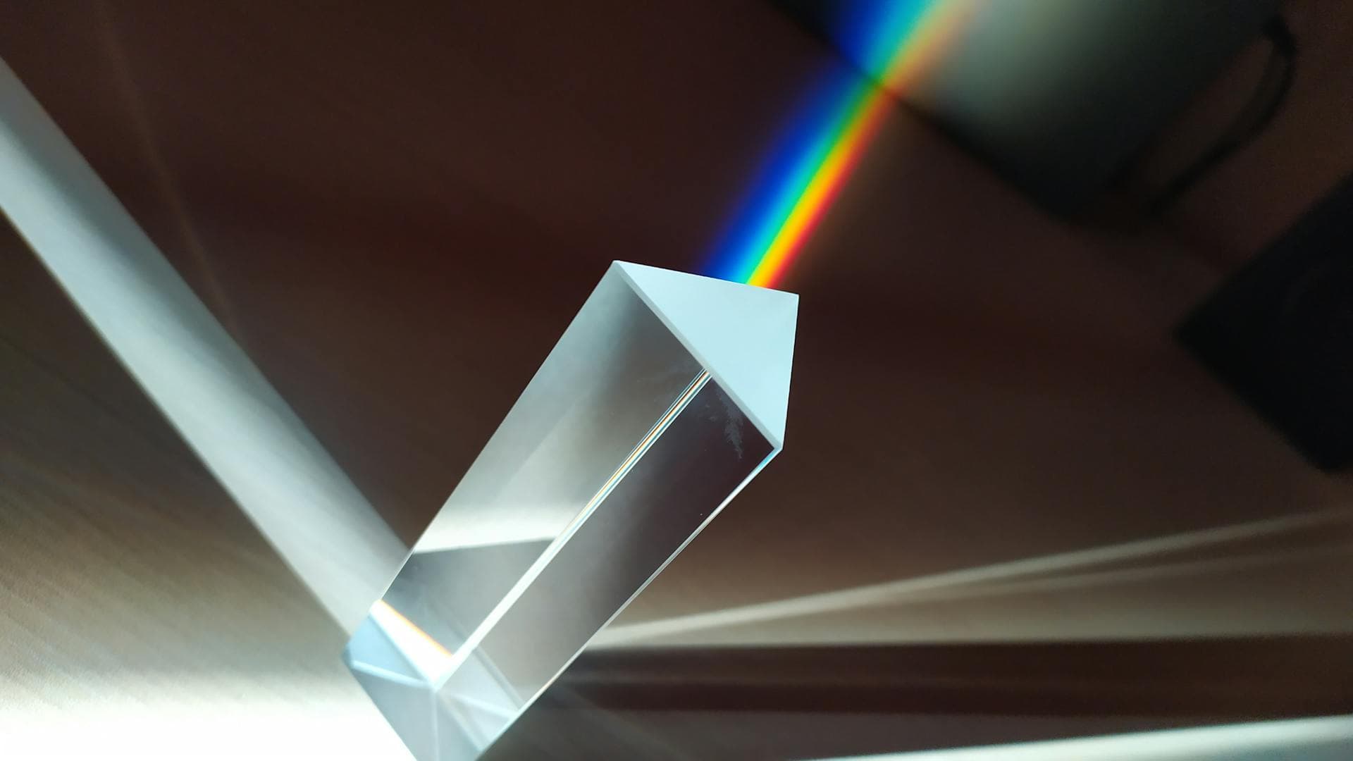 A glass prism dispersing white light into a vivid rainbow spectrum, illustrating color theory