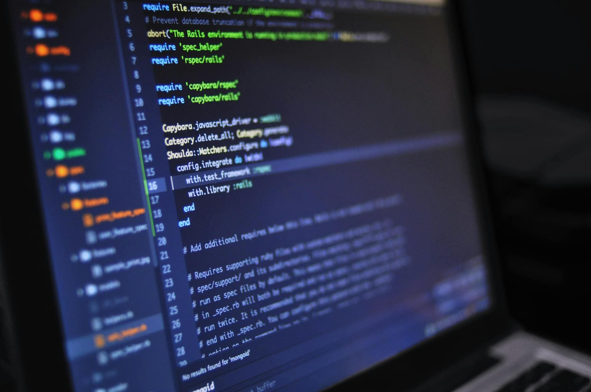 Close-up of a computer screen displaying programming code in a dark environment