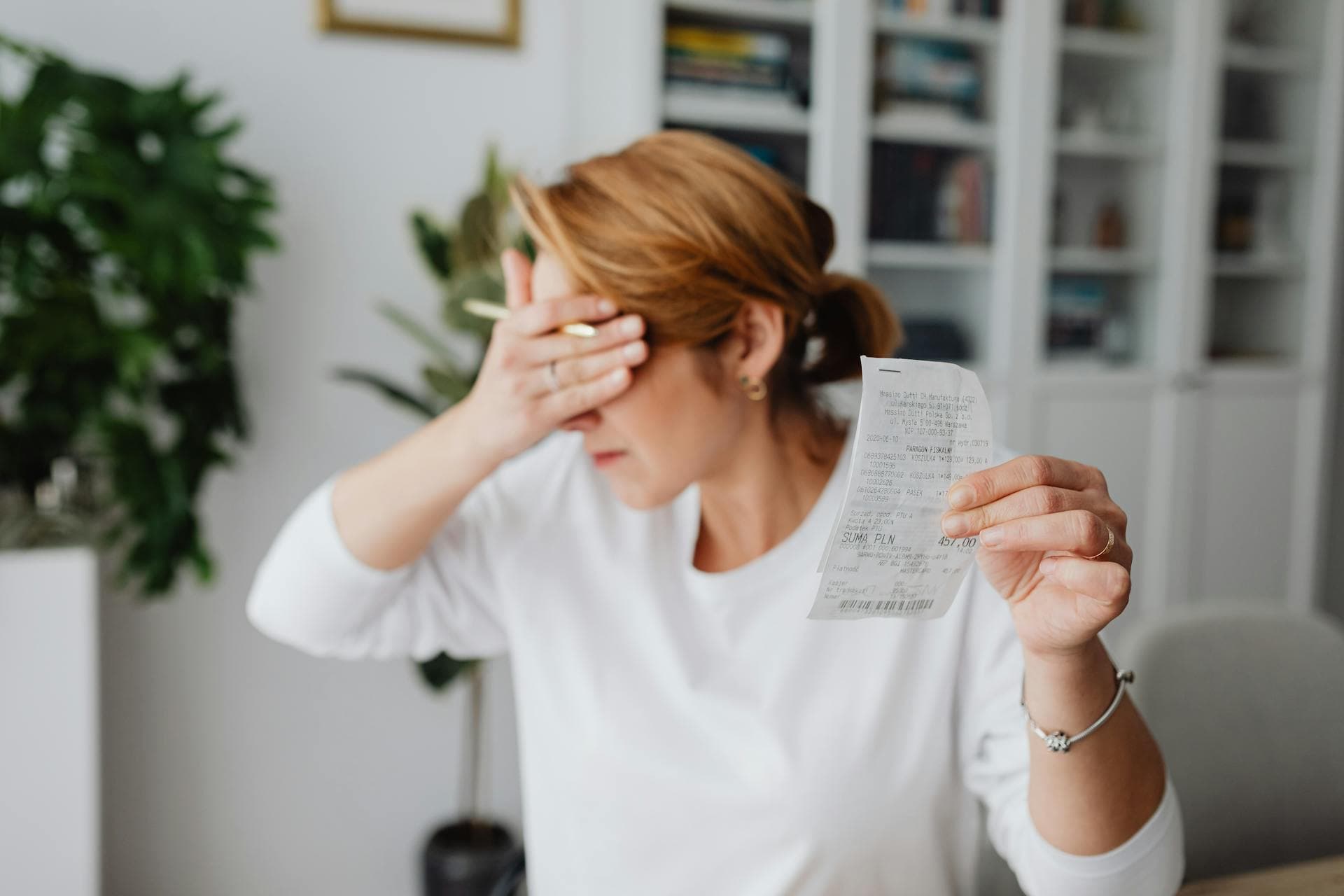 Woman experiencing stress while reviewing household expenses at home