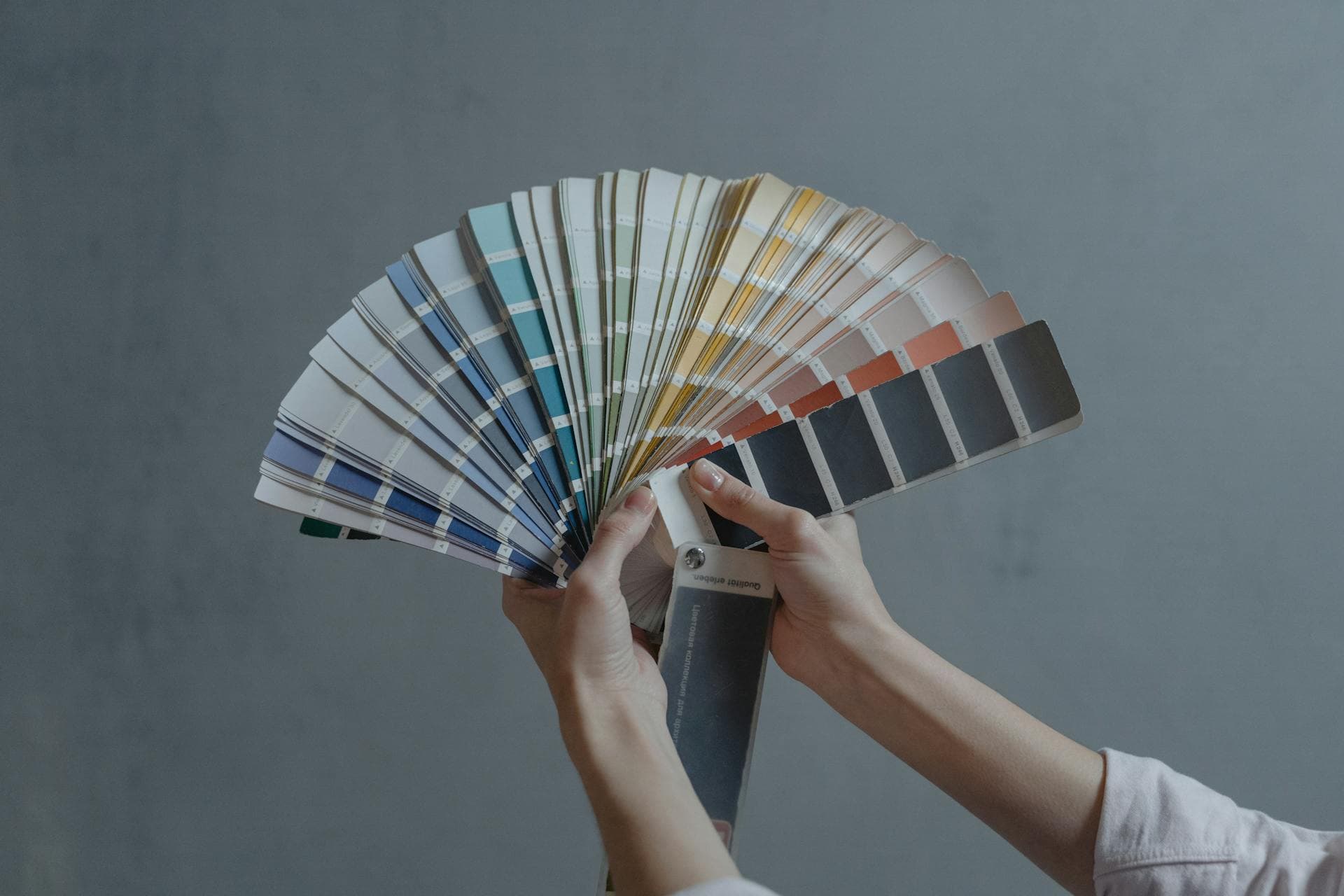 Hands holding a colorful fan of swatches on a gray backdrop, representing theme and color scheme selection